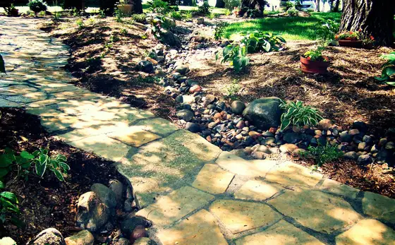 Flagstone walkway crossing a dry creek bed of river rock used for yard drainage