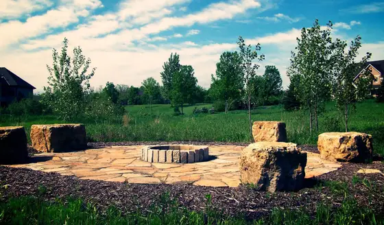 Natural flagstone fire pit with stone block seating set against an open Minnesota meadow