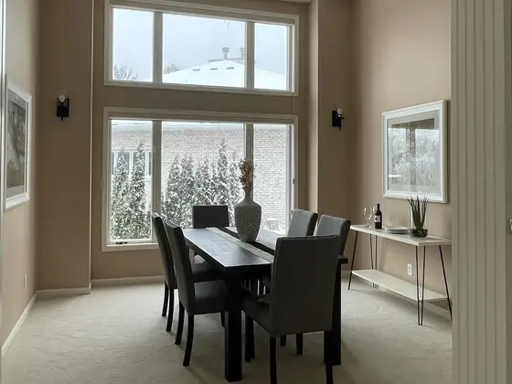 Two-story dining room painted in a soft taupe with white window trim and tall vaulted walls